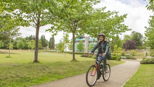 student cycling through woods on path at Lampeter campus