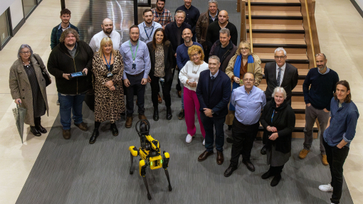 Colour image of people standing in front of staircase with robot dog