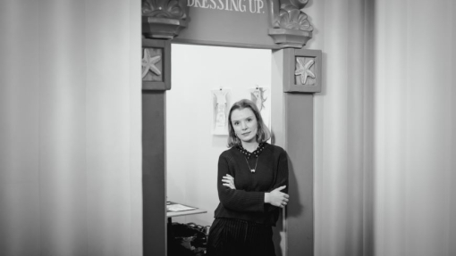 A mono image of a woman standing in a doorway.