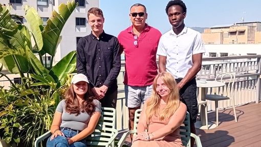 a group of students and lecturers sitting and standing outside 