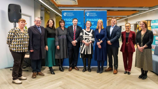 A group of staff and partner companies standing in front of blue branded screens.