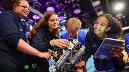Three students and a lecturer involved in a robotics competition.