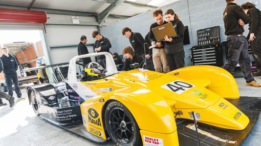 students working on the race car in the pit stop