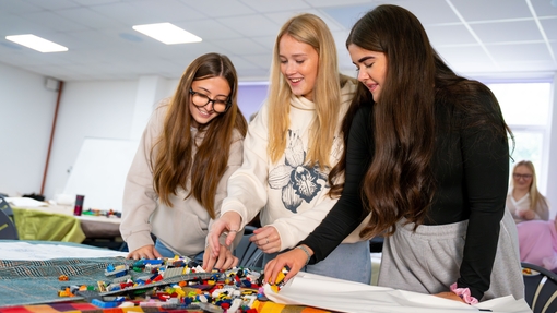 image of three young girls with lego on table in front of them 