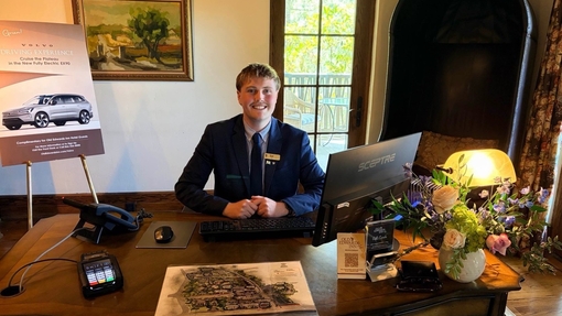 A man standing behind a reception desk smiling