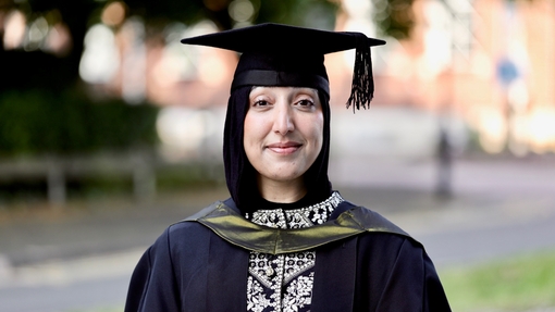 A smiling and proud graduate dressed in her cap and gown.