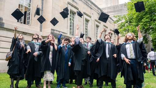 Group of students outside the Brangwyn Hall throwing their graduation hats in the air