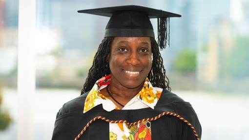 A smiling and proud graduate standing in her cap and gown.
