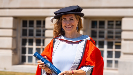 Profile photo of Gabriella Ramos in Honorary Doctorate gown holding certificate outside the Brangwyn Hall