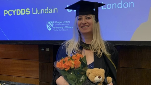 A woman graduating holding flowers and teddy bear