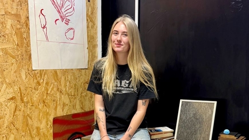 A student in a workshop surrounded by her creative work.