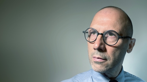 A man wearing glasses and a suit looking slightly off camera.