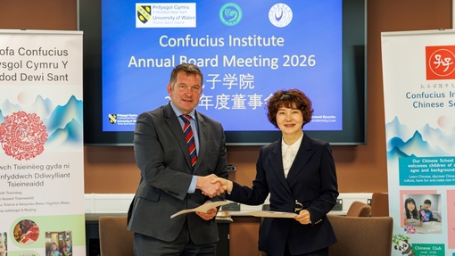 Two people shaking hands against a branded background.