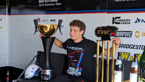 A man sitting in a workshop holding a trophy.