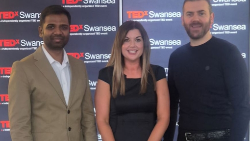 Three people standing against a branded backdrop.