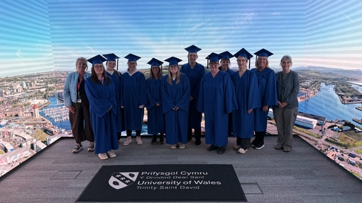 cohort in their cap and gown in immersive room 