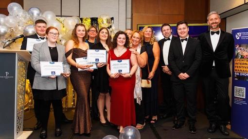 A large group of people in dinner dress celebrating and holding certificates.