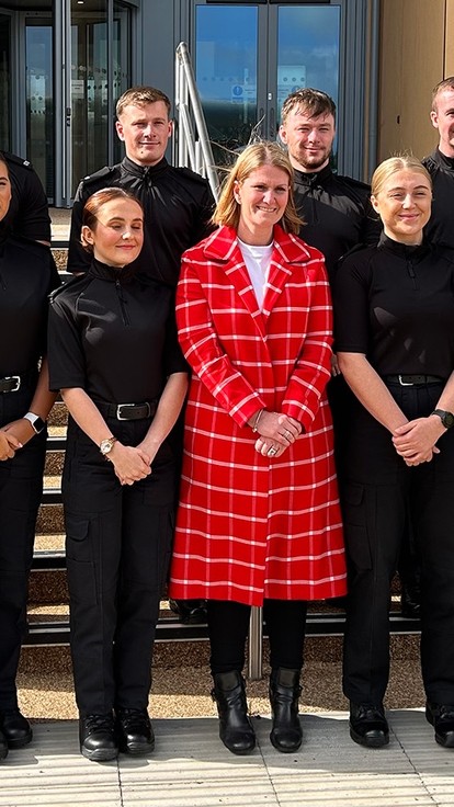 Bronwen Williams stands in the centre of a group of ten black-clad new police officers.