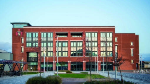 Picture of UWTSD IQ campus made up of red bricks and glass windows under blue skies