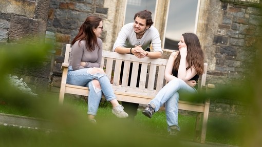 students sitting on bench outside carmarthen