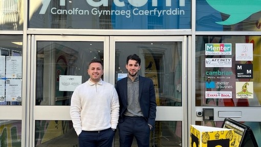 Rhys Young a Kyran Roberts yn sefyll o flaen drysau gwydr Yr Atom.