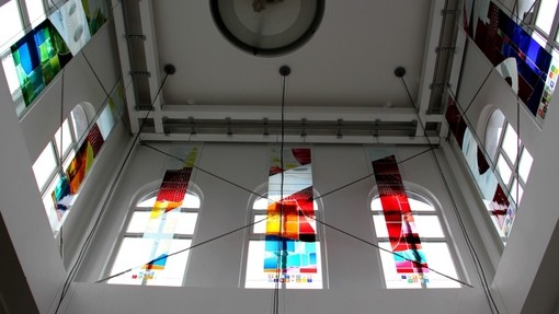 Stain glass panels decorating the plain glass windows of a tower.
