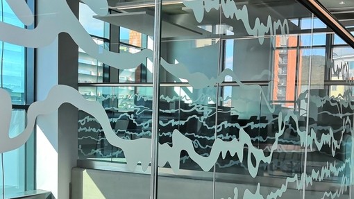 Armchair on a mezzanine in front of a glass panel decorated with white wriggly lines.