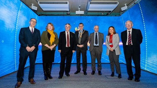 UWTSD senior management and the Lord Mayor of Swansea visiting the fluorescent-blue-walled immersive room.