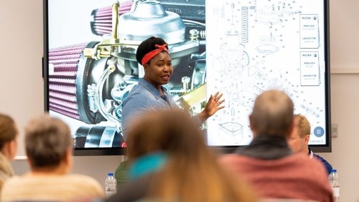 Patricia Mawuli Porter OBE is standing in front of a screen delivering a presentation.