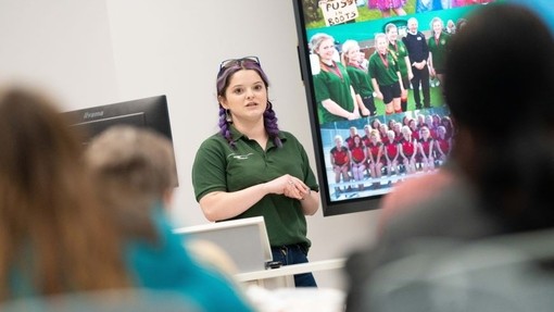 UWTSD Electrical / Electronic Engineering graduate Carys Williams standing in front of a screen delivering a presentation.