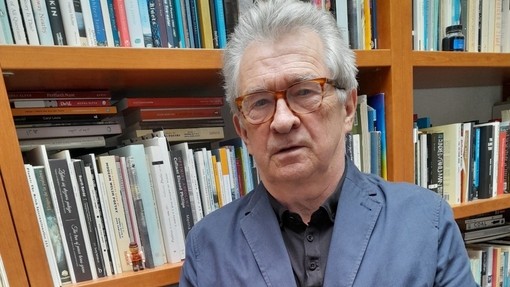 Wynfford James standing in front of crowded bookshelves.