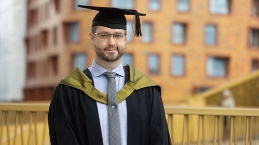 Shaun Kilbane yn gwisgo gŵn academaidd.