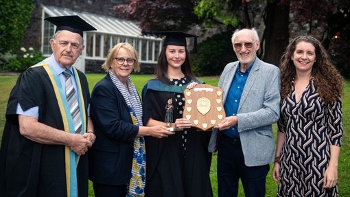 Ffion Anderson yn gafael tarian y wobr gyda Nanna Ryder, Peter Hughes Griffiths a’i theulu’n bresennol.