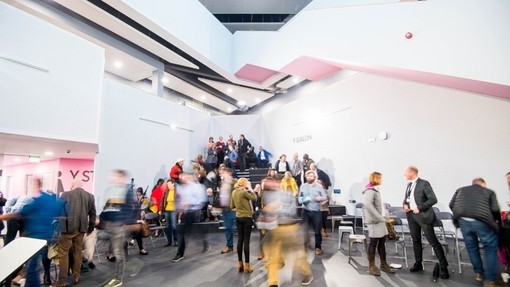 A modern white atrium bustling with people.