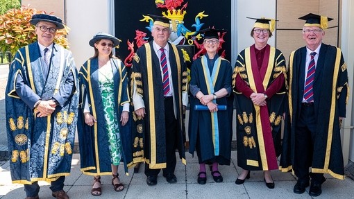 Saif Dr Ceridwen Lloyd-Morgan yn gwenu gydag uwch aelodau’r Brifysgol, gan gynnwys yr Athro Heather Williams.