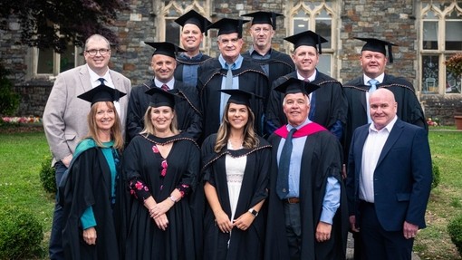 Y graddedigion mewn gwisg academaidd o flaen yr Hen Adeilad, Campws Caerfyrddin.