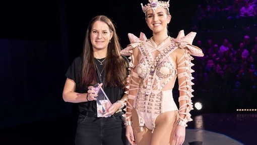 Agi Olah wrth ymyl model sy’n gwisgo’i dyluniad buddugol – Beneath - ar gyfer cystadleuaeth Wearable Art.