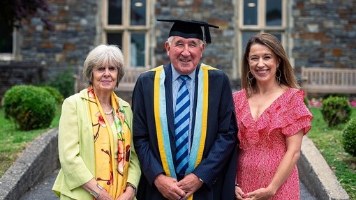 Yn sefyll gyda’i deulu, gwena Eifion Griffiths yn llydan.