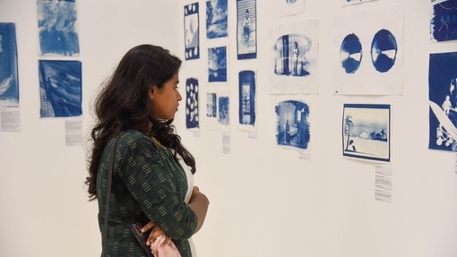 Mae dynes yn archwilio’r cyanotypes sydd i’w gweld yn yr arddangosfa.
