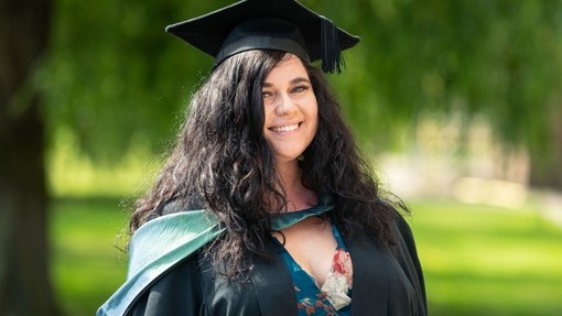 Laura Cait Driscoll yn gwenu yn ei gynau graddio.