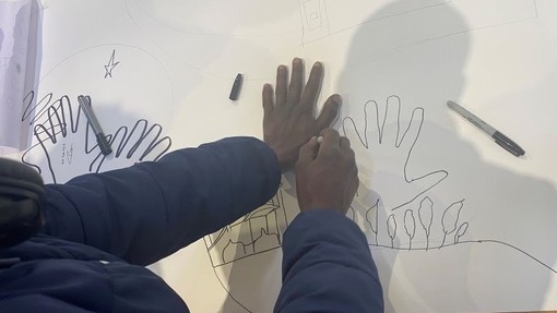 A person outlines the shape of their hand as part of a larger artwork.