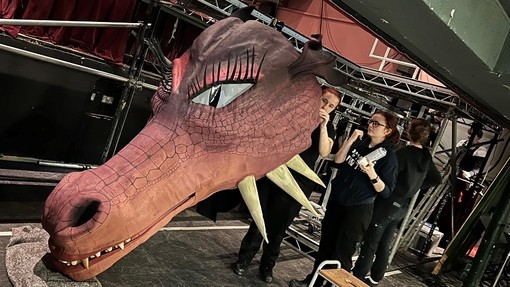 Two women inspect a detail at the back of the dragon head.