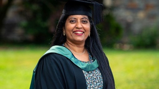 Anupa Paul yn gwenu mewn gwisg academaidd.