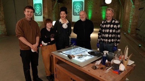 Kerry Collison yn sefyll wrth fainc waith mewn ystafell ganoloesol gromennog yng nghwmni Billy Bailey, John Reyntiens ac eraill.