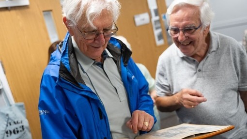 Friends from the class of '63 look through a photo album.