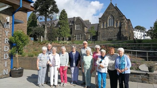Nine women and two men from the class of '63 smile for a group photo; the Chapel and the Old Building are visible behind them.
