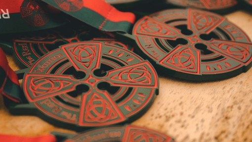 A pile of Red Warrior medals with a Celtic cross design.