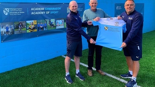 Academy of sport and Carmarthen town AFC Staff holding a t-shirt