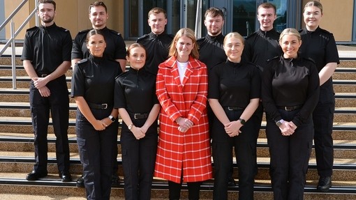 Bronwen Williams yn sefyll yng nghanol grŵp o ddeg o heddweision newydd yn eu lifreion du.