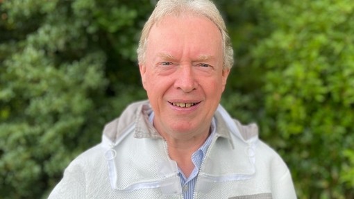 Selwyn Runnett yn gwisgo oferôl gwenynyddiaeth.